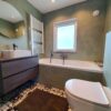 Badkamer met ligbad, toilet en wastafelmeubel afgewerkt met Beton Ciré in een wat diepere kleur groen, maar niet te donker. De kleur Palm 5.8. De vloer is afgewerkt met patchwork tegelvloer